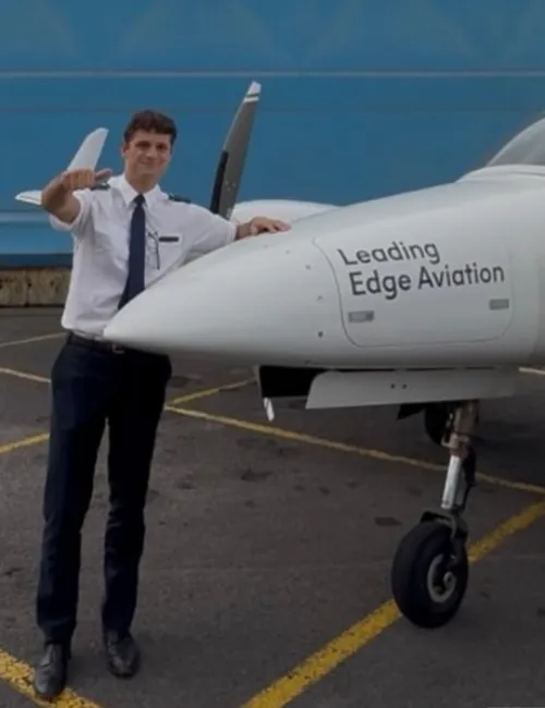 Charlie standing beside a training aircraft, giving a thumbs up